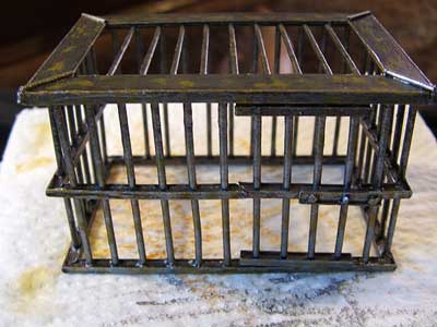 Finished miniature jail cell built from black-painted styrene beams and bars, including its working barred door